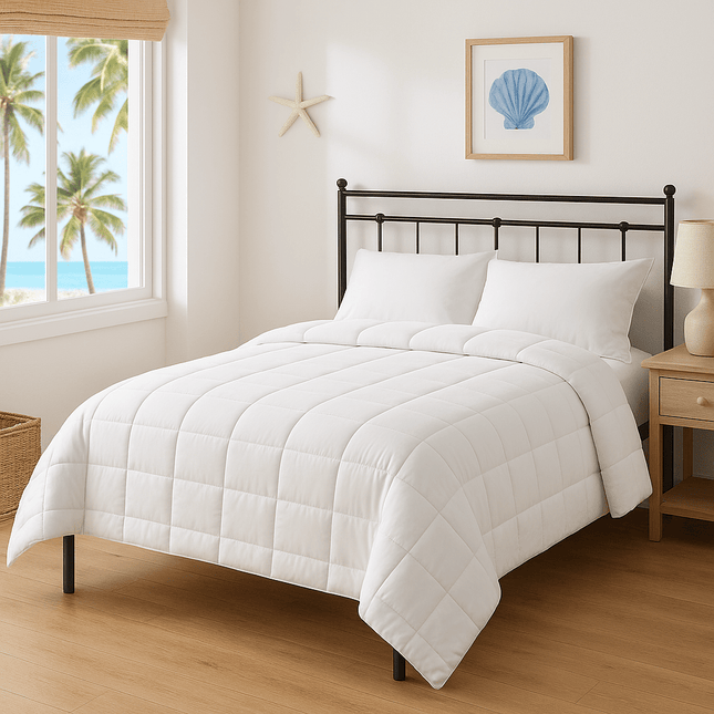 White comforter on a bed in a bright bedroom with a window view of palm trees.