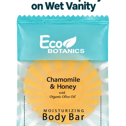 A packaged Eco Botanics Chamomile & Honey moisturizing body bar wrapped in a bright aqua waterproof wrap, with text above and below explaining that the wrap keeps unused soap dry on wet vanity. The soap itself is visible through the clear lower section and appears yellow with a sunburst pattern.