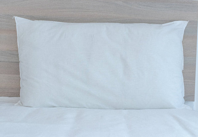 White pillow on a bed with a wooden headboard
